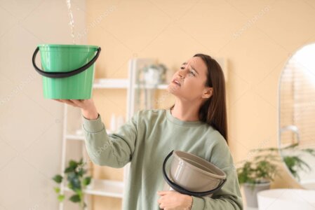 Seau et serpillière sous une fuite d’eau au plafond